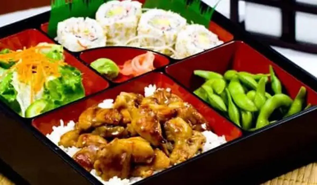 Japanese bento box with teriyaki chicken, sushi roll, salad, and edamame
