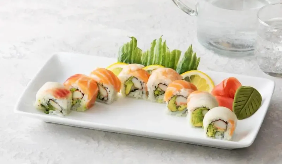 Salmon topped sushi roll with avocado and crab filling served with lemon garnish
