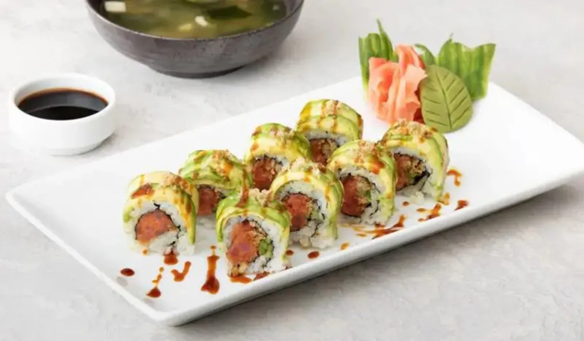 Avocado topped sushi roll with fresh tuna filling and decorative sauce