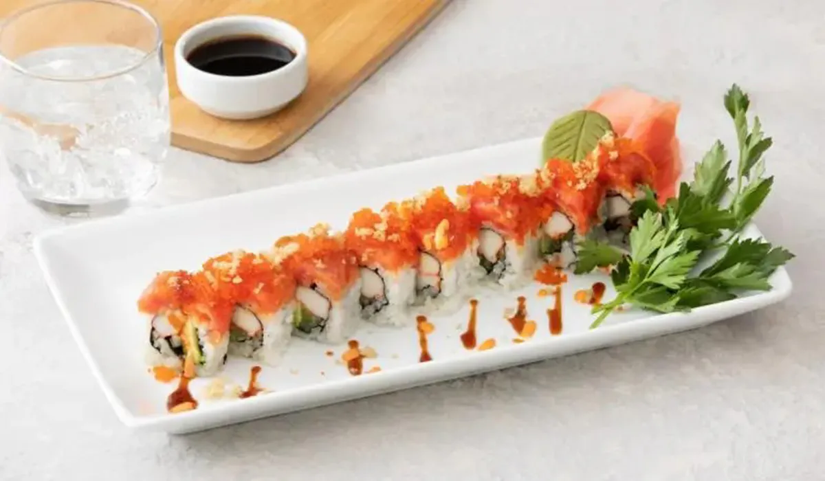 Special sushi roll topped with spicy crab and orange masago on a white plate
